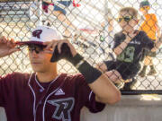 Jude Amundsen, 4, whose family is hosting a Raptors’ player, peers over the shoulder of Ridgefield’s Wyatt Hoffman while the team prepares for the first pitch on opening day Tuesday at the new Ridgefield Outdoor Recreation Complex. The team played their first home game Tuesday night in their inaugural season in the West Coast League.