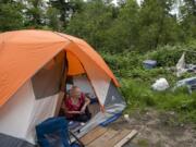 Christy Jordan, 56, looks out from her tent in a wooded area in Hazel Dell. She says that all the heaps of garbage nearby were left by campers who have since left and that she keeps her trash in a bag nearby. During her three years of being homeless, she’s camped out in parks in Vancouver. She says she was once given a 72-hour notice to leave by police and cleared out. “I listen to the cops; I’m a good girl,” she said.