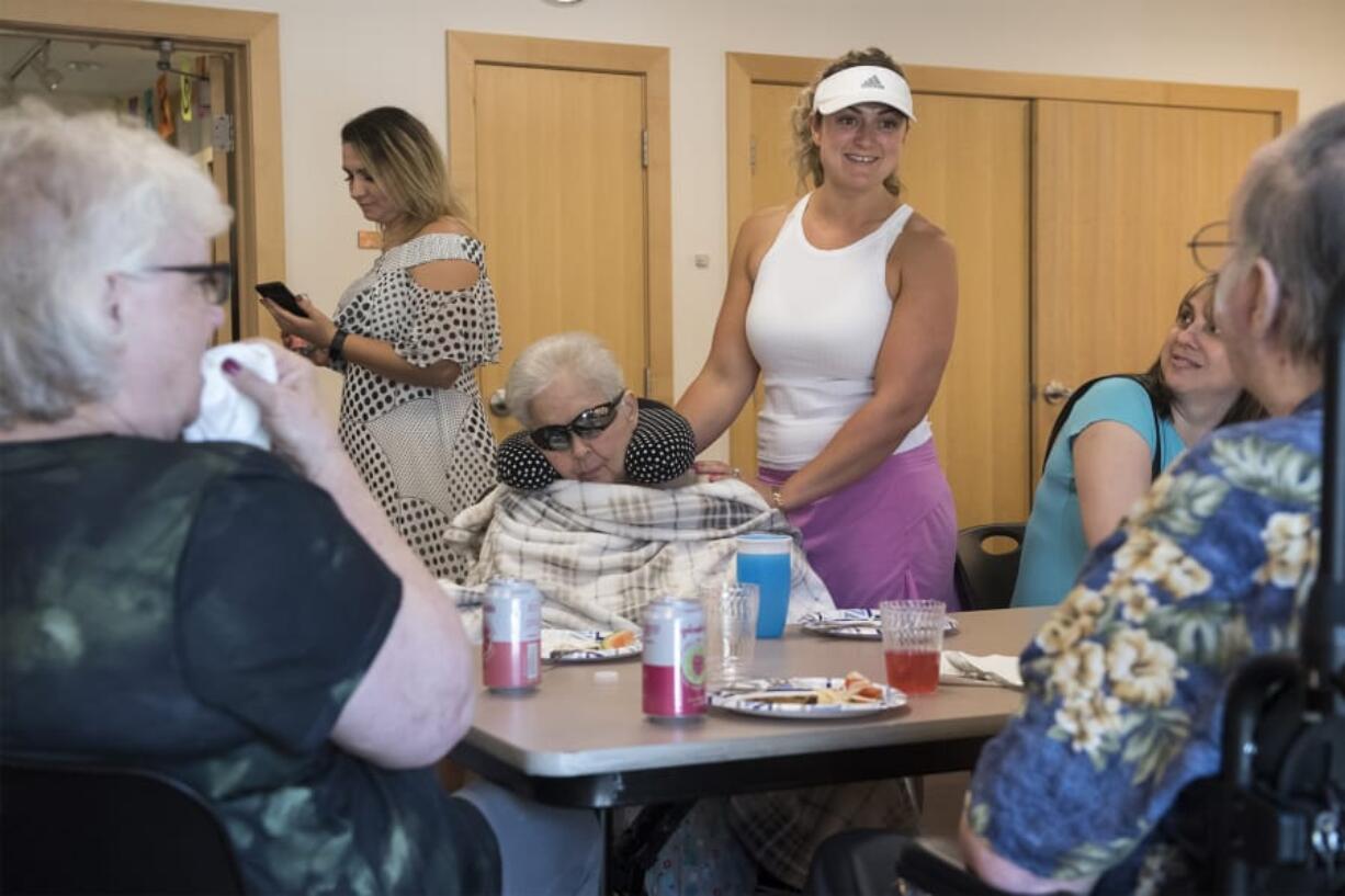 Rita Ulrich, 81, center, and Mera Cosgrove, center right, speak with residents of Magda’s Adult Care during an art show Thursday afternoon at Three Creeks Community Library. Magda’s hosted an art show of the residents’ work and honored recently deceased resident Tauno Alanko.