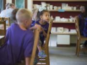 Nivea Bonde listens as her class from Children’s Village of Orchards Daycare is given a demonstration on painting at Earth, Glaze and Fire.