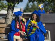 Milkana Ghebretensae, left, and Abesha Kebede share a joke while waiting for the start of the Clark College commencement ceremony at the Sunlight Supply Amphitheater on Thursday night. Both are Running Start students, graduating with both their associate degrees and their high school degrees.