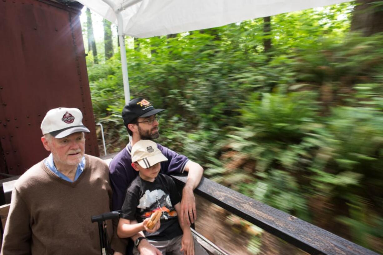 Tom Smith, his son Allen Smith and grandson Eric Smith, 8, ride the Chelatchie Prairie Railroad in Yacolt on Father’s Day. At top, Jerry Jacobus punches tickets for passengers boarding the train Sunday.