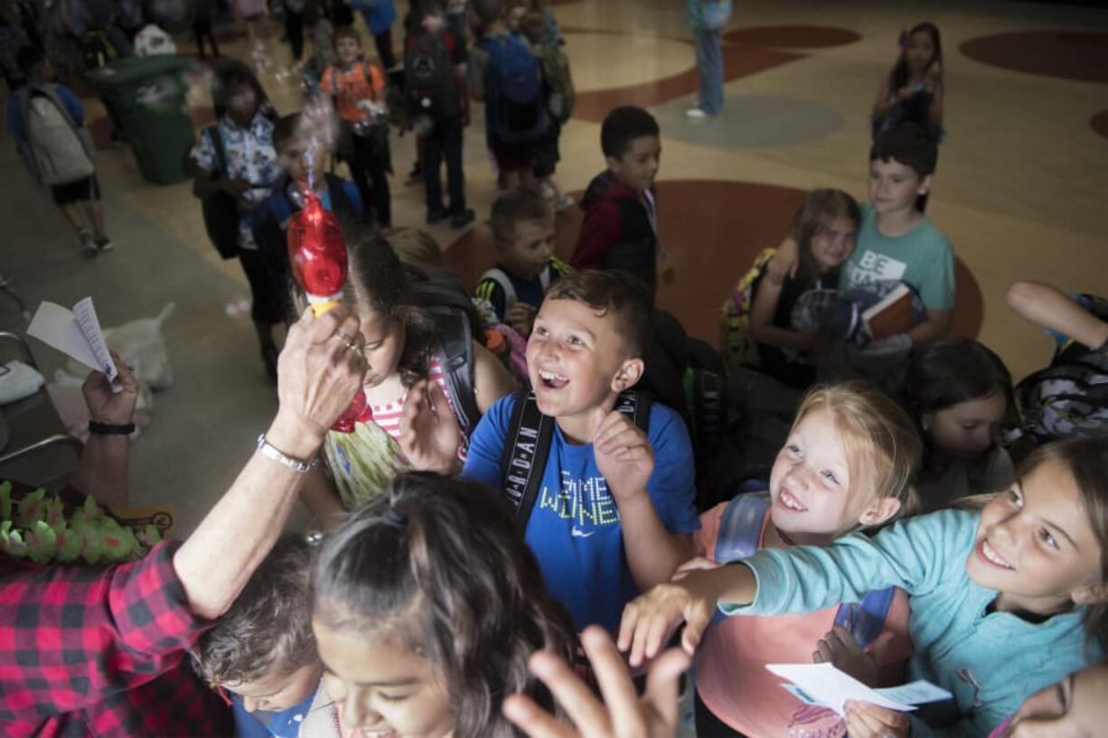 Students at Dorothy Fox Elementary School try to catch bubbles on the last day of school Thursday. At Dorothy Fox, staffers and parents blow bubbles at students as they exit the building on their last day.