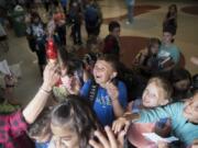 Students at Dorothy Fox Elementary School try to catch bubbles on the last day of school Thursday. At Dorothy Fox, staffers and parents blow bubbles at students as they exit the building on their last day.