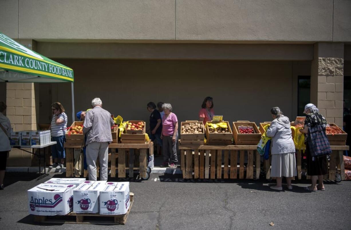 People pick out fresh produce during a food pantry event with the Clark County Food Bank outside the Women, Infants and Children office in Vancouver on Wednesday.