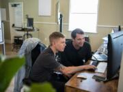 Digital marketing specialist Zach Losness, left, looks over team photos with CEO Andy Lowery at the RealWear headquarters in Vancouver on Friday. The company has secured a new $80 million funding round and hopes to nearly double its staff in Vancouver by the end of the year.