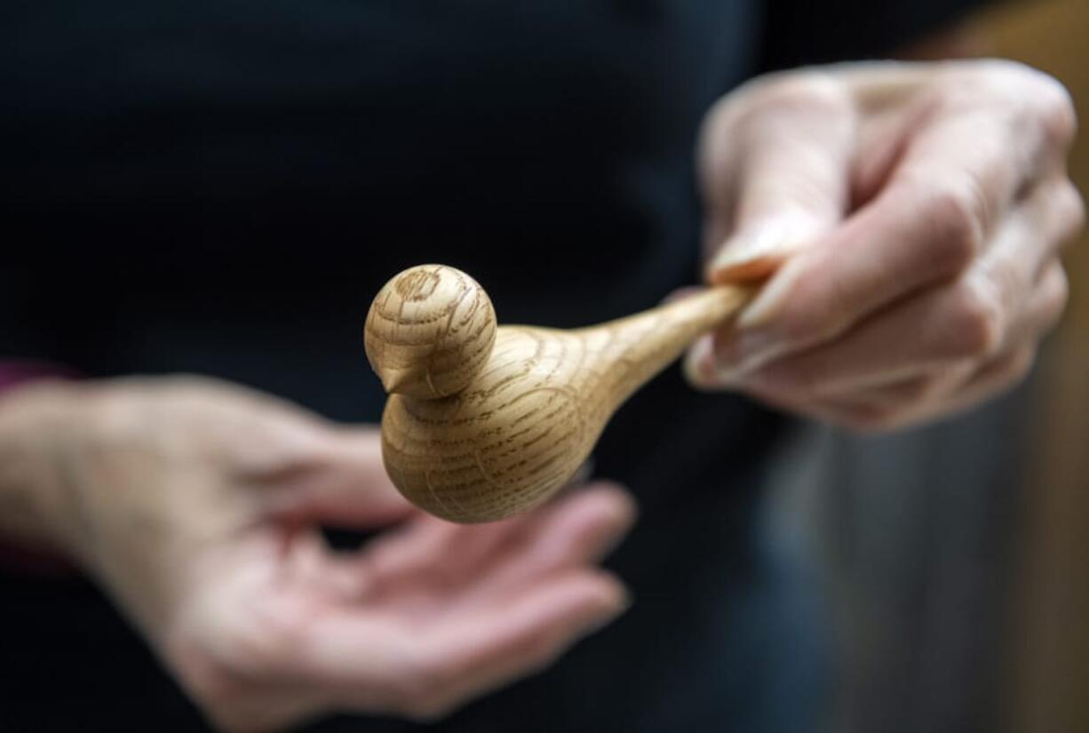 Clark County woodturner Kathleen Duncan shows a little wooden bird that she just finished turning and assembling at her home workshop in Mount Vista.