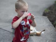 Hunter Randolph, 4, washes down his lunch with a carton of apple juice Friday at Kiwanis Community Park in Battle Ground.