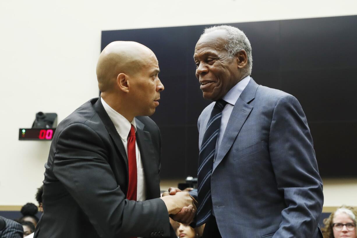 Democratic Presidential candidate Sen. Cory Booker, D-NJ, left, greets Actor Danny Glover, before they testify about reparations for the descendants of slaves, during a hearing before the House Judiciary Subcommittee on the Constitution, Civil Rights and Civil Liberties, at the Capitol in Washington, Wednesday, June 19, 2019.