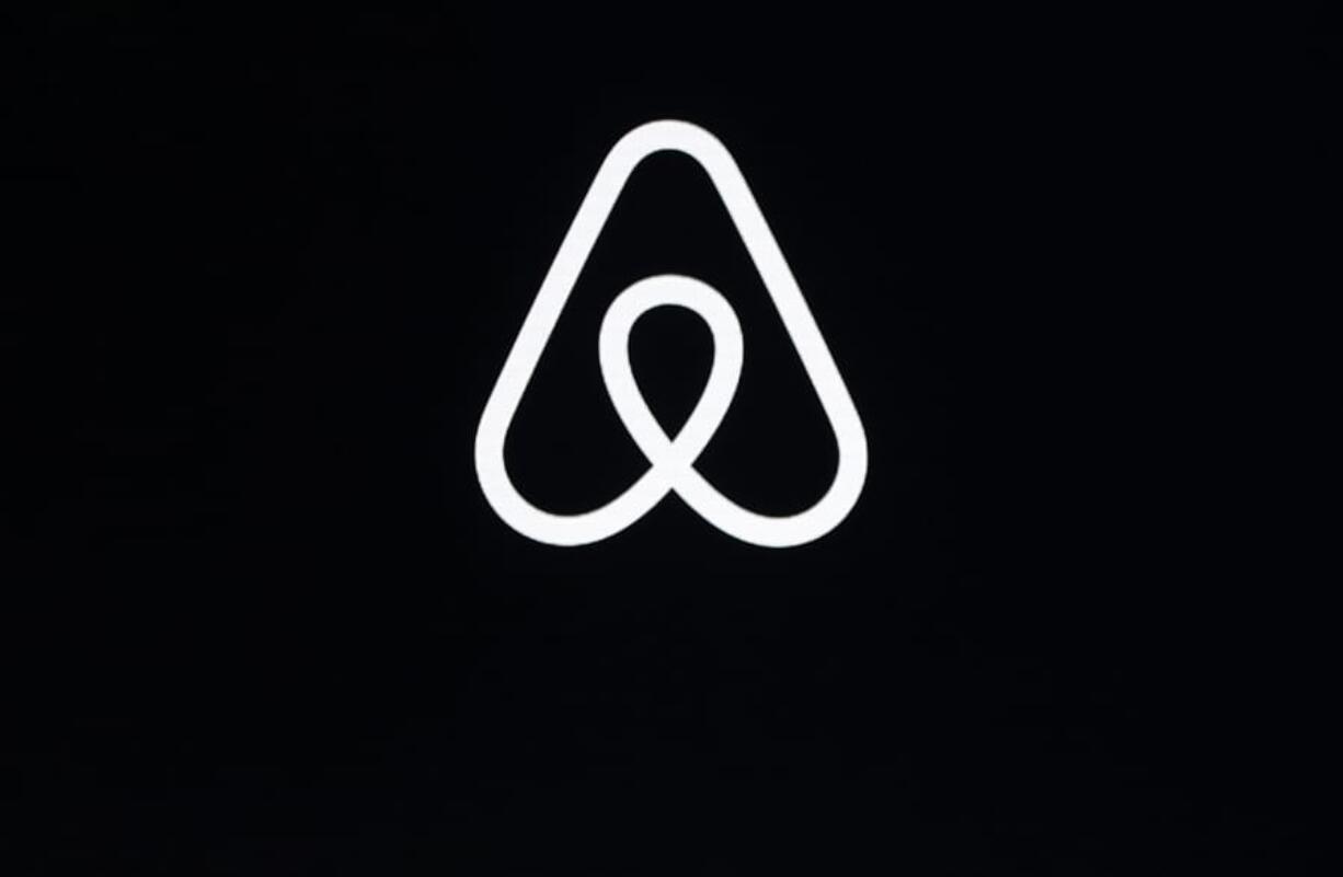 FILE - This Feb. 22, 2018, file photo shows an Airbnb logo during an event in San Francisco. A lucky few will be able to live the adventures of Phileas Fogg from Jules Vernes’ classic “Around the World in 80 Days.” Hosted by Airbnb, a small number of guests will travel across 16 countries to promote a new collection of available bookings called Airbnb Adventures.