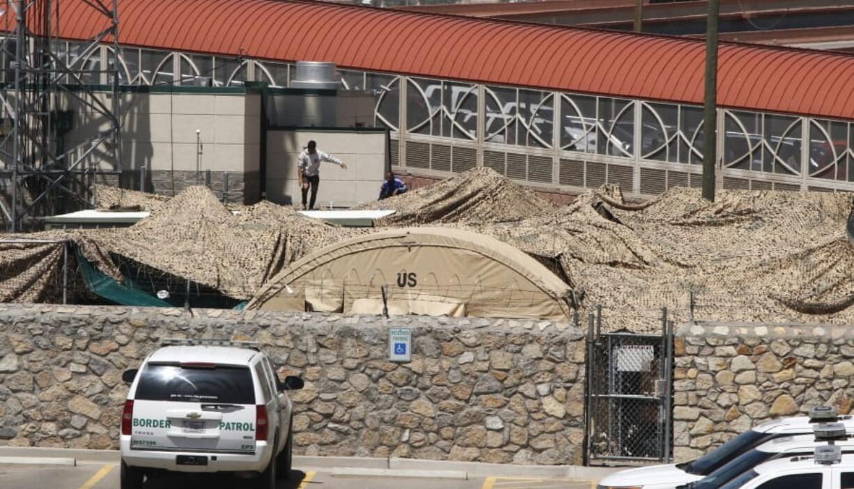 In this June 7, 2019, photo, migrants adjust a shade canopy over an outdoor encampment where they’re waiting to be processed by immigration in El Paso, Texas. The Trump administration is facing growing complaints from migrants about severe overcrowding, meager food and other hardships at border holding centers like this one.