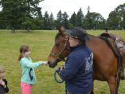 Emmalynn Covey, 10, of Portland taps a horse at Get Outdoors Day at Fort Vancouver National Historic Site. Get Outdoors Day, which is held at various sites nationally, is focused on promoting outdoor activities.