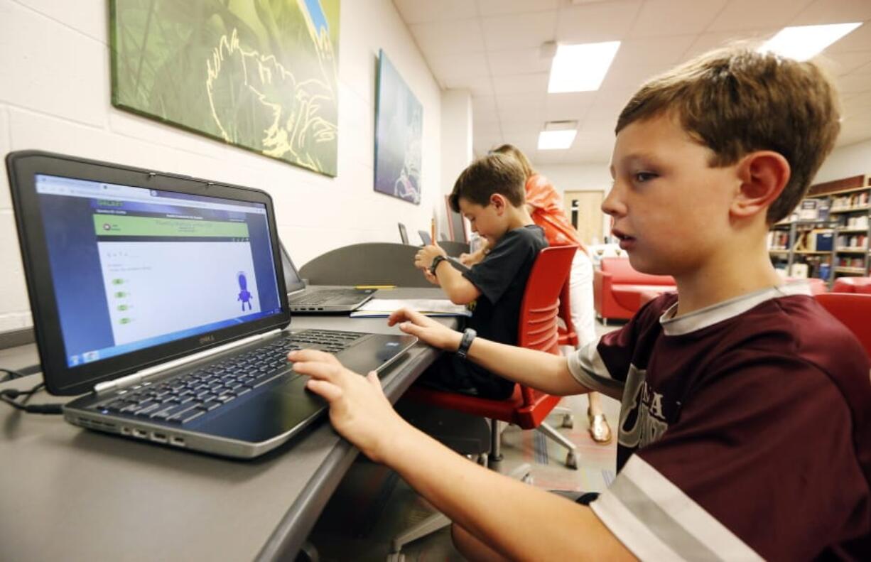 Third-grade student Miles Stidham uses an East Webster High School laptop to do homework May 8 in Maben, Miss. The Stidhams are unable to get internet at their home in the country, so they take advantage of the internet in the school’s library. Rogelio V.