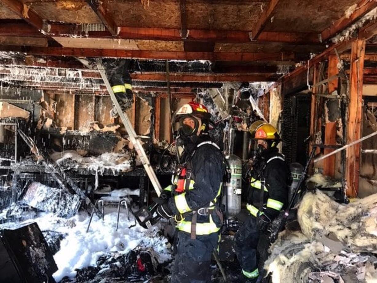 Firefighters inspect a house in Vancouver's Northwest neighborhood after it was devastated by fire Sunday afternoon. The fire killed one dog.