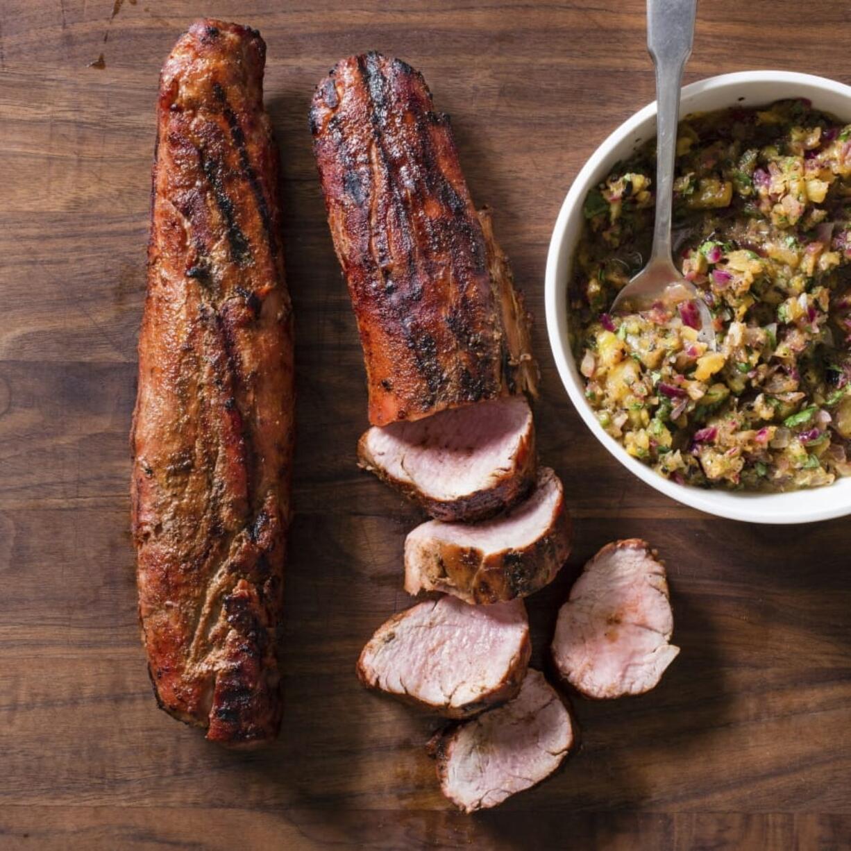 This undated photo provided by America’s Test Kitchen in June 2019 shows Grill Roasted Pork Tenderloin with Grilled Pineapple Red Onion Salsa.