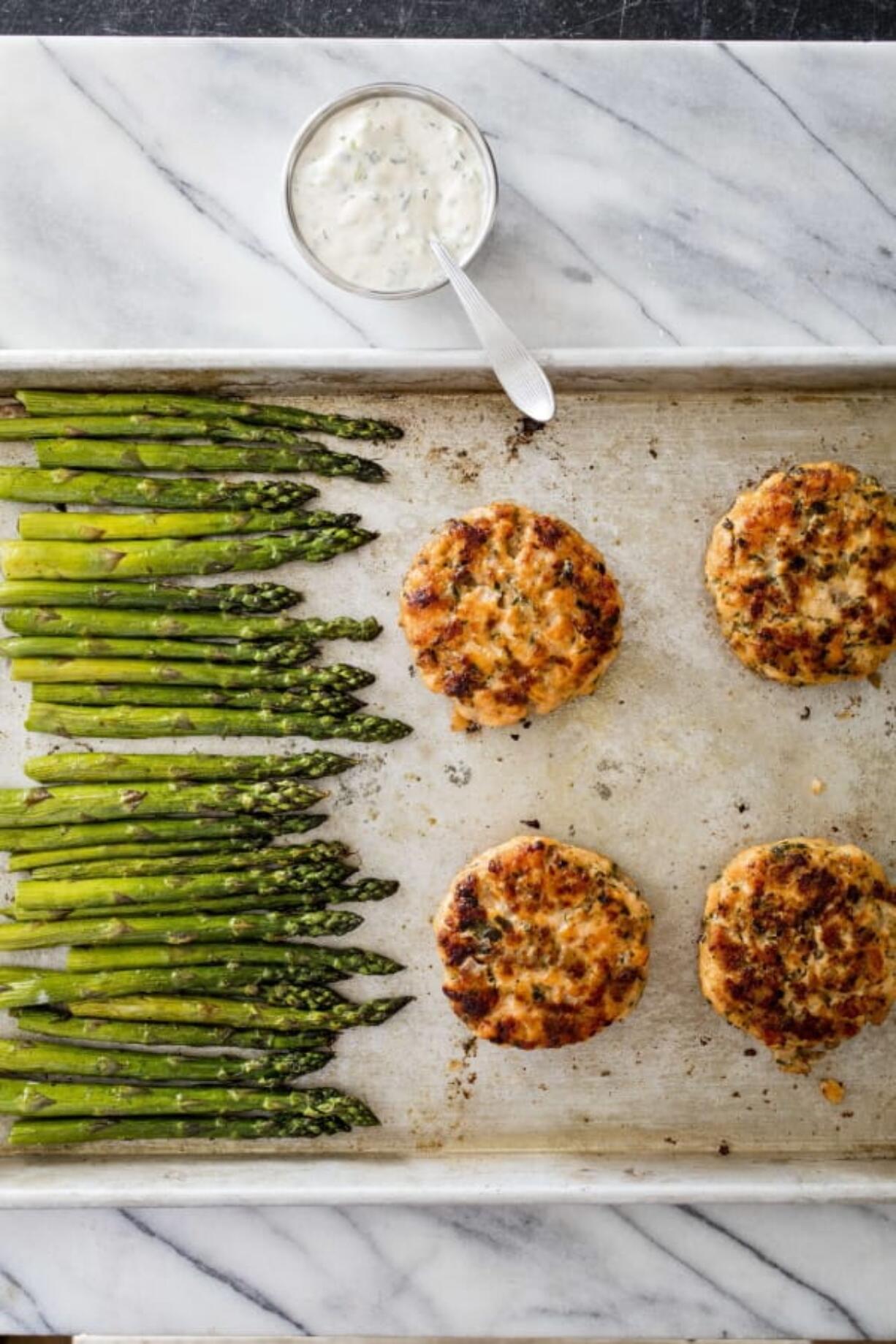 This undated photo provided by America’s Test Kitchen in June 2019 shows Salmon Burgers. This recipe appears in the cookbook “One-Pan Wonders.” (Daniel J.