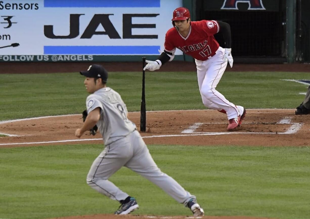 Los Angeles Angels’ Shohei Ohtani, right, runs to first for a single as Seattle Mariners starting pitcher Yusei Kikuchi runs to back up the first baseman during the first inning of a baseball game Saturday, June 8, 2019, in Anaheim, Calif. (AP Photo/Mark J.