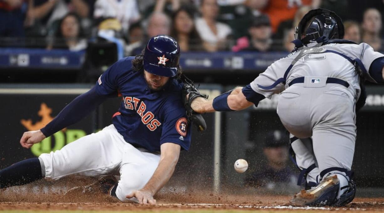 Houston Astros’ Jake Marisnick, left, slides safely past Seattle Mariners catcher Tom Murphy to score on Jose Altuve’s two-run double during the eighth inning of a baseball game, Sunday, June 30, 2019, in Houston.