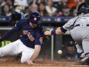 Houston Astros’ Jake Marisnick, left, slides safely past Seattle Mariners catcher Tom Murphy to score on Jose Altuve’s two-run double during the eighth inning of a baseball game, Sunday, June 30, 2019, in Houston.