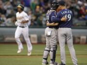 Seattle Mariners pitcher Wade LeBlanc, right, speaks with catcher Omar Narvaez as they wait for Oakland Athletics' Marcus Semien, back left, to run the bases after hitting a home run in the second inning of a baseball game Saturday, June 15, 2019, in Oakland, Calif.