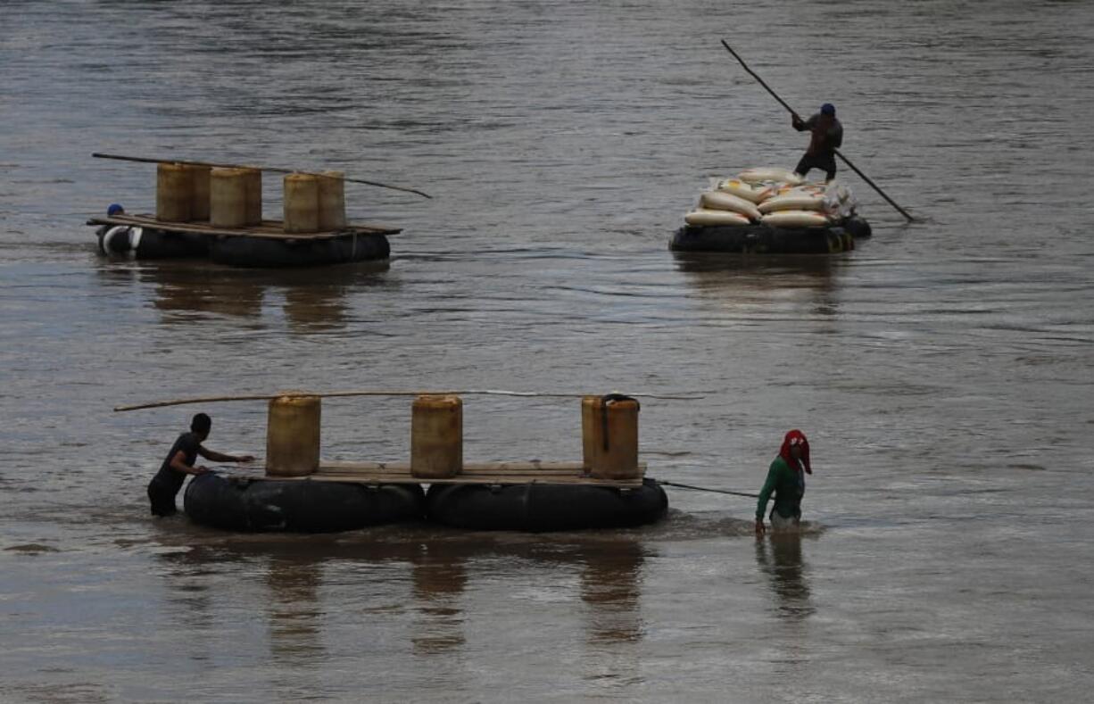 Men use rafts to transport black-market gasoline across the Suchiate River from Guatemala to Mexico, as one pushes sacks of corn in the opposite direction to Guatemala, near Ciudad Hidalgo, Mexico, Thursday, June 6, 2019. U.S. President Donald Trump has pledged to impose 5 percent tariffs on Mexican products unless Mexico country prevents Central American migrants from traveling through its territory. Some migrants pay raft operators in order to avoid swimming or going through the official border crossing.