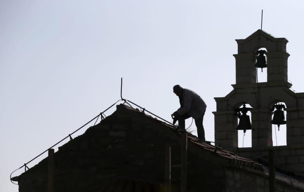 In this Wednesday, March 15, 2017 file photo, a worker fixes roof on Holy Sunday church in the ‘Tsar’s Village’ complex near Sveti Stefan peninsula in Montenegro. A Serb official has branded Montenegro a “criminal” state and threatened a “fierce” response over the neighboring country’s plans to introduce a church law. The draft law calls for all religious communities in Montenegro to provide proof that they owned their property before 1918 when the small Adriatic state lost its independence and became part of the Serb-dominated Kingdom of Serbs, Croats and Slovenes. If they don’t, the property becomes state owned.