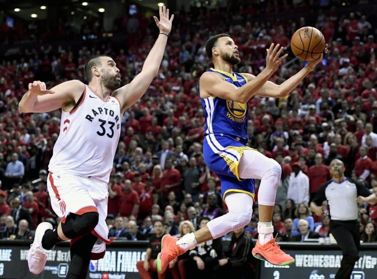 Golden State Warriors guard Stephen Curry (30) drives to the net as Toronto Raptors center Marc Gasol (33) looks on during the first half of Game 2 of basketball’s NBA Finals, Sunday, June 2, 2019, in Toronto.