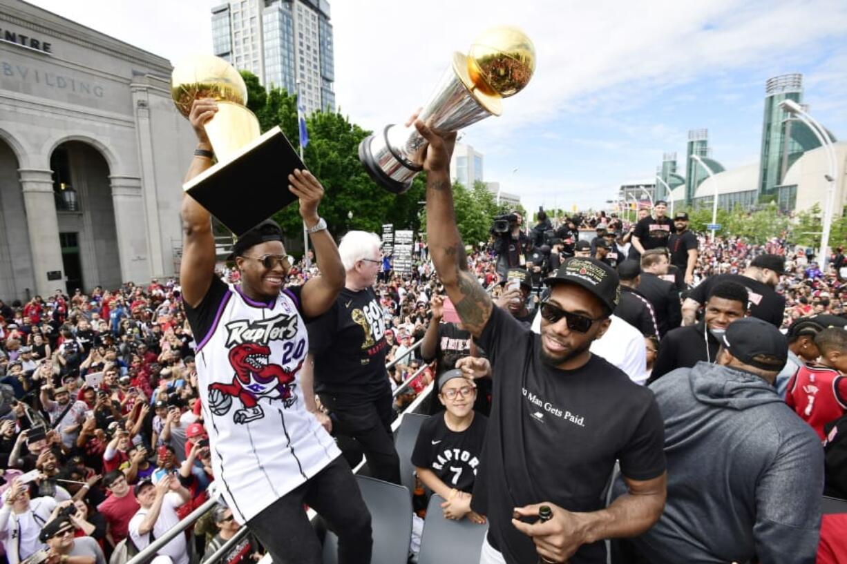 Toronto Raptors guard Kyle Lowry, left, holds the Larry O’Brien Championship Trophy as forward Kawhi Leonard holds his playoffs MVP trophy during the NBA basketball championship team’s victory parade in Toronto, Monday, June 17, 2019.