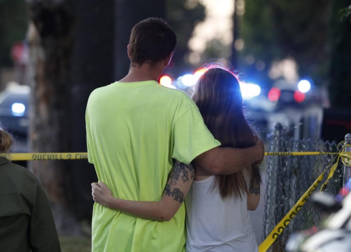 A man and woman watch as law enforcement officers surround a home where a gunman has taken refuge after shooting a Sacramento police officer, Wednesday, June 19, 2019, in Sacramento, Calif.