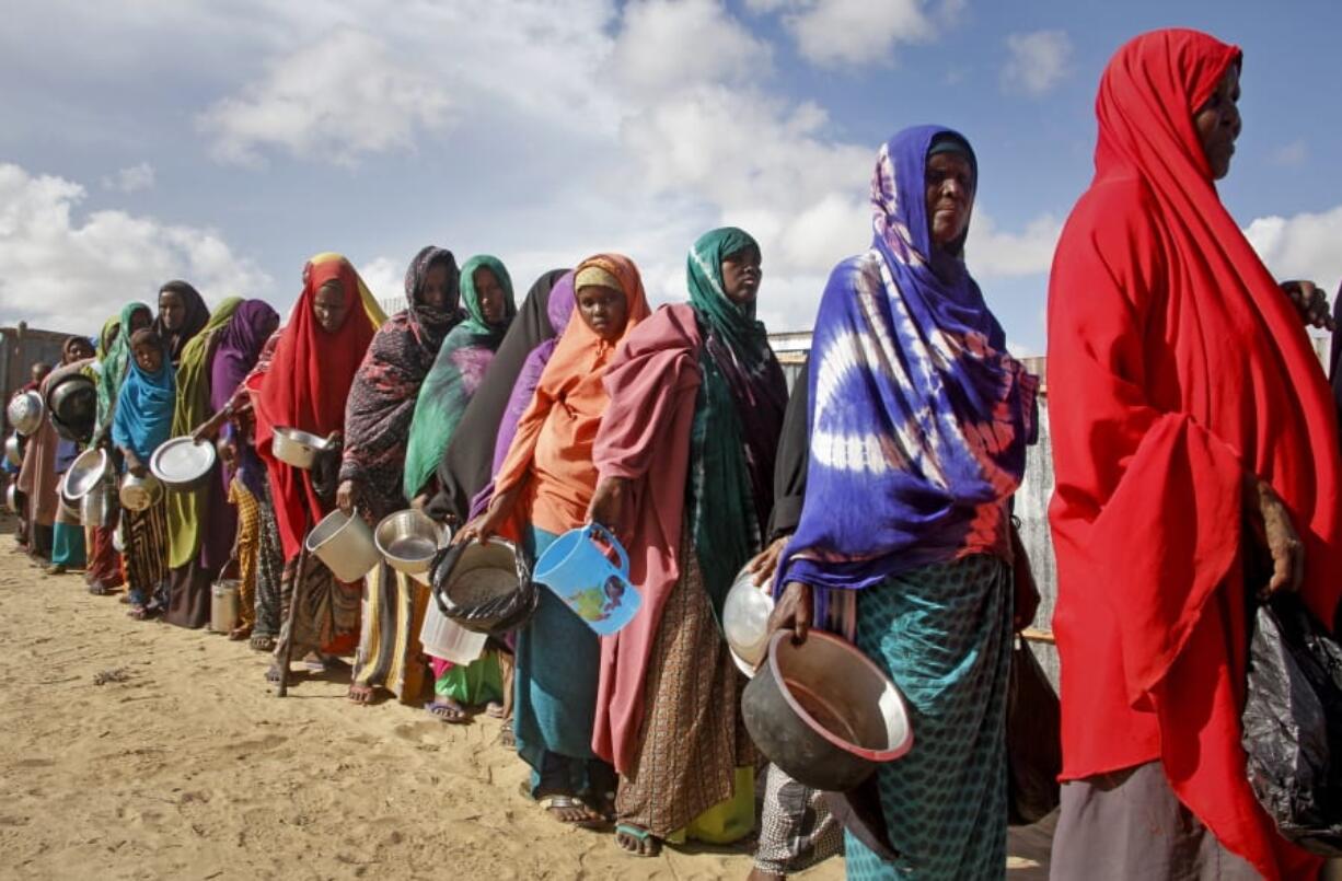 FILE - In this Saturday, May 18, 2019 file photo, newly-arrived women who fled drought line up to receive food distributed by local volunteers at a camp for displaced persons in the Daynile neighborhood on the outskirts of the Somalian capital Mogadishu.