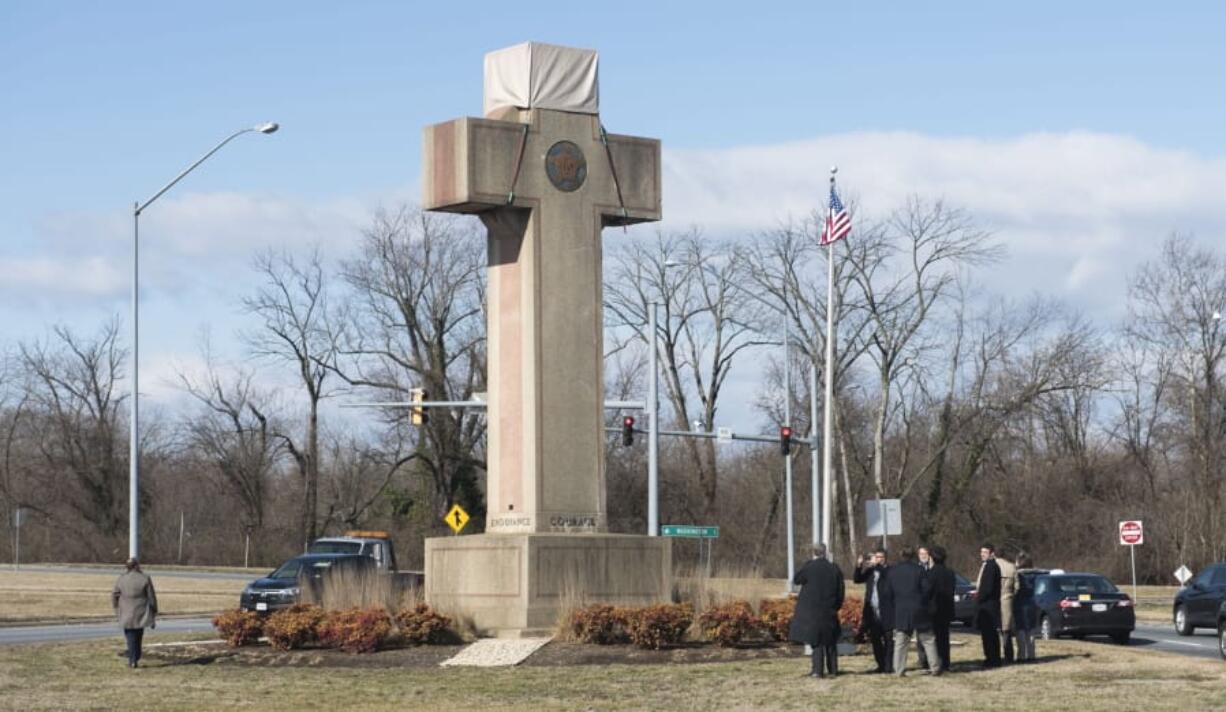 FILE - In this Feb. 13, 2019 file photo, visitors walk around the 40-foot Maryland Peace Cross dedicated to World War I soldiers in Bladensburg, Md. The Supreme Court says the World War I memorial in the shape of a 40-foot-tall cross can continue to stand on public land in Maryland. The high court on Thursday rejected a challenge to the nearly 100-year-old memorial. The justices ruled that its presence on public land doesn’t violate the First Amendment’s establishment clause.