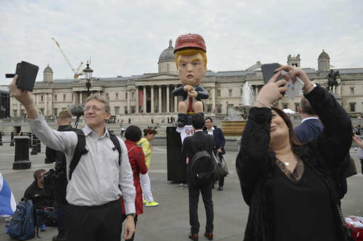 Commuters and tourists take selfies backdropped by a 16ft talking robot depicting US President Donald Trump sitting on a gold toilet in Trafalgar Square, London, on Tuesday June 4, 2019. Some protest groups are using the State Visit to the UK by US President Donald Trump to demonstrate against various issues. The National Gallery in background.