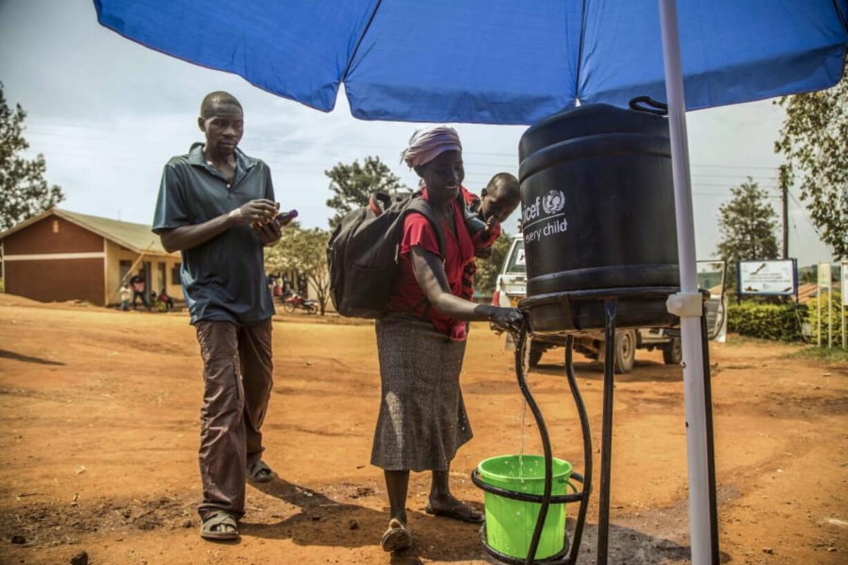 In this photo provided by the International Rescue Committee, Congolese refugees wash their hands before being screened for Ebola symptoms at the IRC triage facility in the Kyaka II refugee settlement in Kyegegwa District in western Uganda, Thursday, June 13, 2019. The Congolese pastor who is thought to have caused the Ebola outbreak’s spread into Uganda was unknown to health officials before he died of the disease, the World Health Organization’s emergencies chief said Thursday, underlining the problems in tracking the virus.