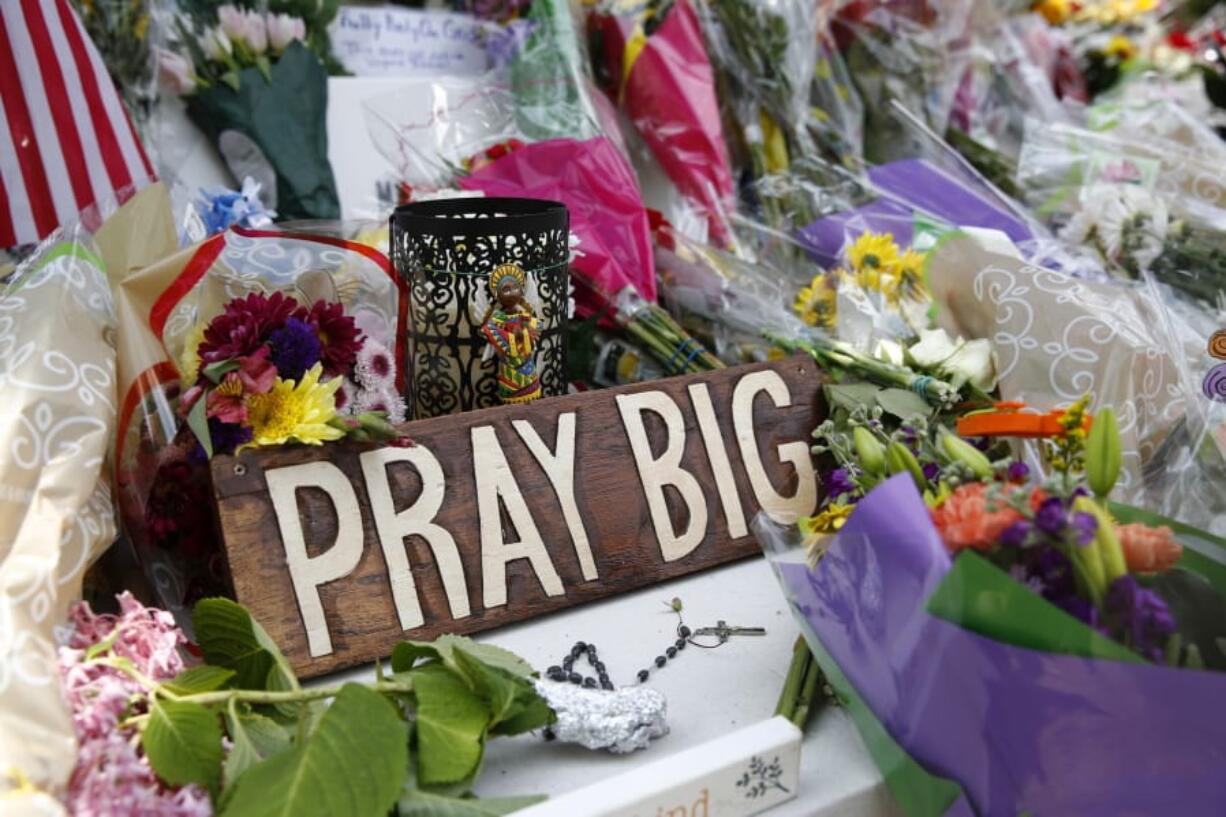 A sign sits among flowers and mementos left at a makeshift memorial for victims of a mass shooting at a municipal building in Virginia Beach, Va.