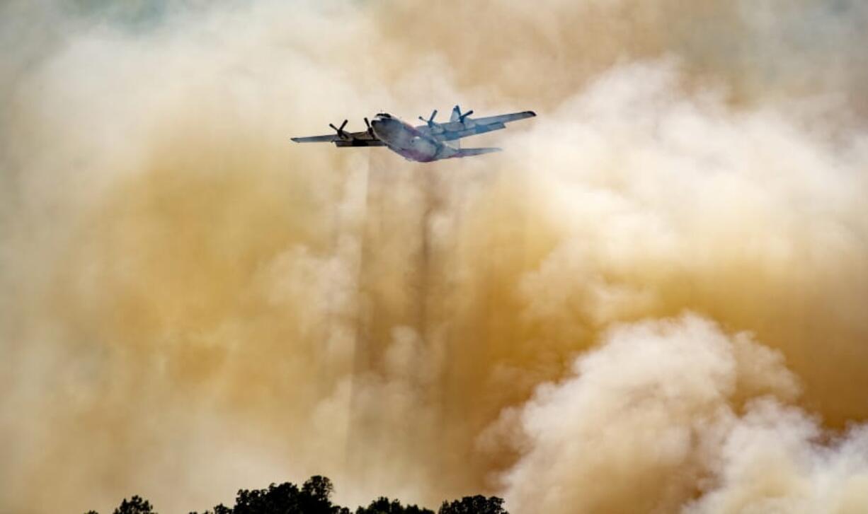 A firefighting aircraft flies through smoke after dropping fire retardant on a hillside in an attempt to box in flames from a wildfire locally called the Sand Fire in Rumsey, Calif., Sunday, June 9, 2019.