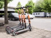 Commuters pass by a row of parked SPIN electric scooters May 17 on Southwest Naito Parkway in downtown Portland.  (Bryan M.