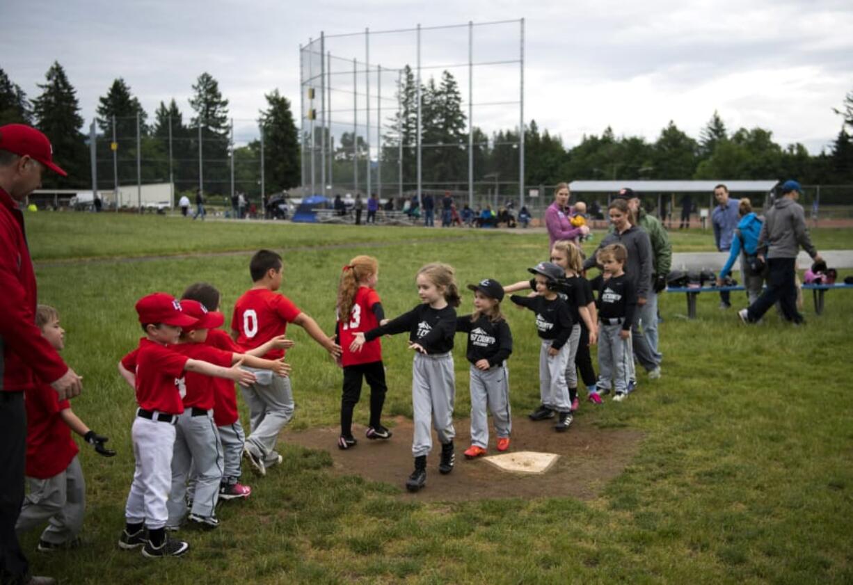 Two East County Little League teams high-five after their game May 21 at George Schmid Memorial Park in Washougal. The park will get a third baseball field thanks to a state grant.