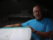 Luke Alvarez, owner of Generic Brand Surfboards, stands with a custom-made surfboard in his shed in Tuckerton, New Jersey on Wednesday, June 11, 2014.