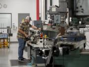 Andy Doty, a computer numerical control machinist at Sigma Design, makes a set of screws on a lathe.