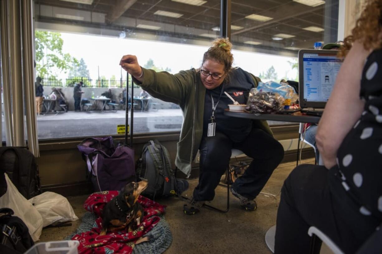 Lisa Wattles feeds her niece’s dog, Eddie, at the Vancouver Navigation Center in Vancouver on June 27. Wattles said she comes to the day center every day for a safe place to hang out. Attendance at the day center has far exceeded initial estimates, with staff and volunteers serving more than 1,400 people.