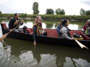 Washington State University Pullman graduate student Chelsea Ratzlaff, center, dips her fingers in Lake River as her classmates paddle in Kthlmin, a 36-foot, 15-person Chinook Indian Nation canoe. The vessel was donated to the tribe in 2011 by the descendents of William Clark who, with Meriwether Lewis, stole a canoe from the Chinook people in 1806 before leaving the West Coast.