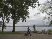 Vancouver resident Doug Ruecker strolls under overcast conditions with his daughter’s dog, Tony, a 3-year-old chow mix, while enjoying the morning at Wintler Community Park on Friday. Ruecker said he was happy for mild temperatures. “I prefer the cooler weather,” he said.