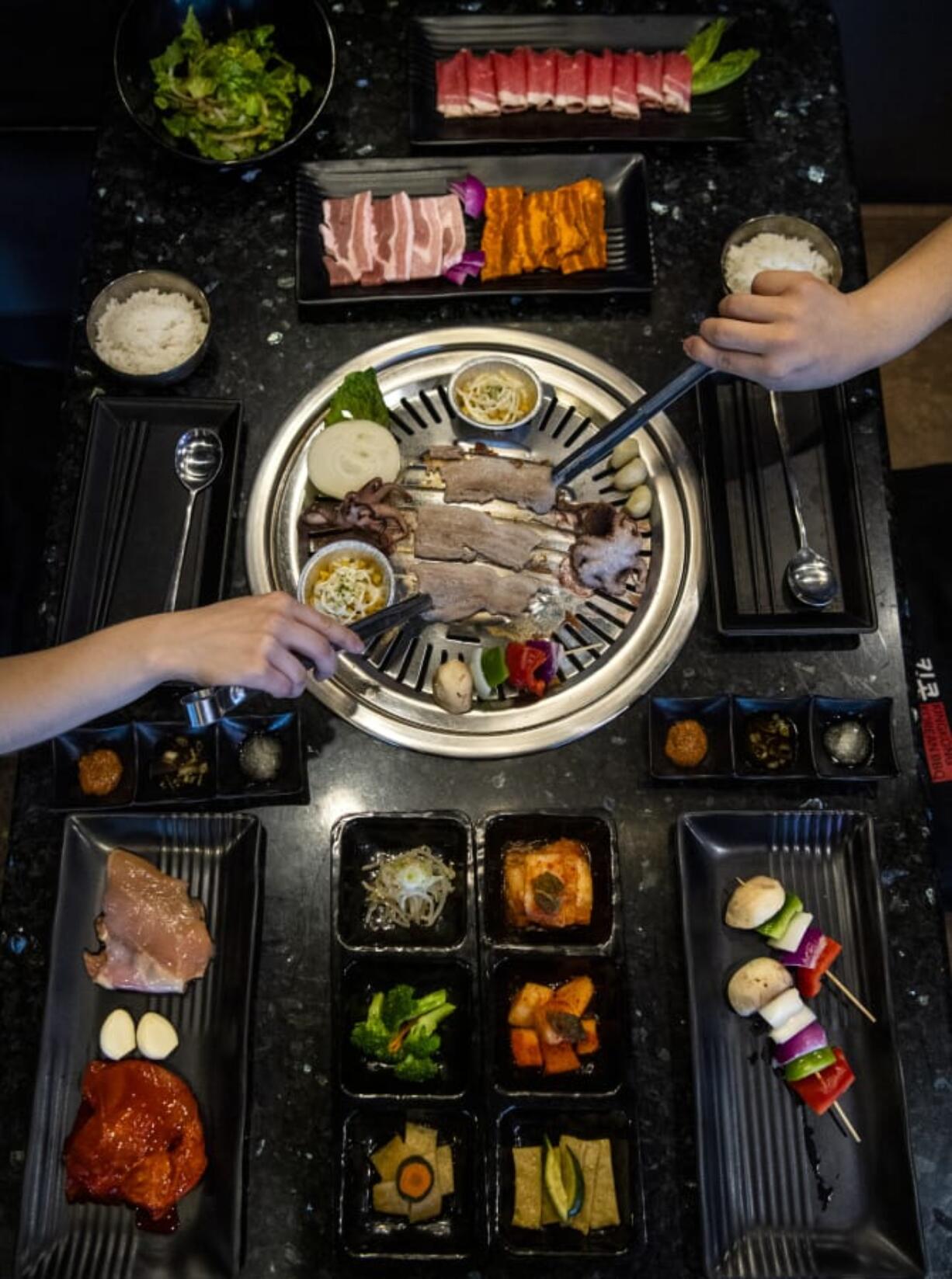 Pork belly, baby octopus, corn and veggie skewers are placed on the grill to cook at KingKong Korean BBQ in Vancouver.