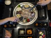 Pork belly, baby octopus, corn and veggie skewers are placed on the grill to cook at KingKong Korean BBQ in Vancouver.