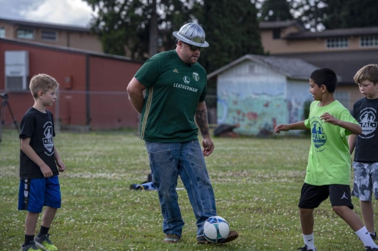 Julian Charbonneau, from left, Portland Timbers mascot Joey Webber, also known as Timber Joey, with Ezequiel Valencia and Chase Anderson, kick the ball around during a game of keep away Thursday morning at Fruit Valley Elementary School.