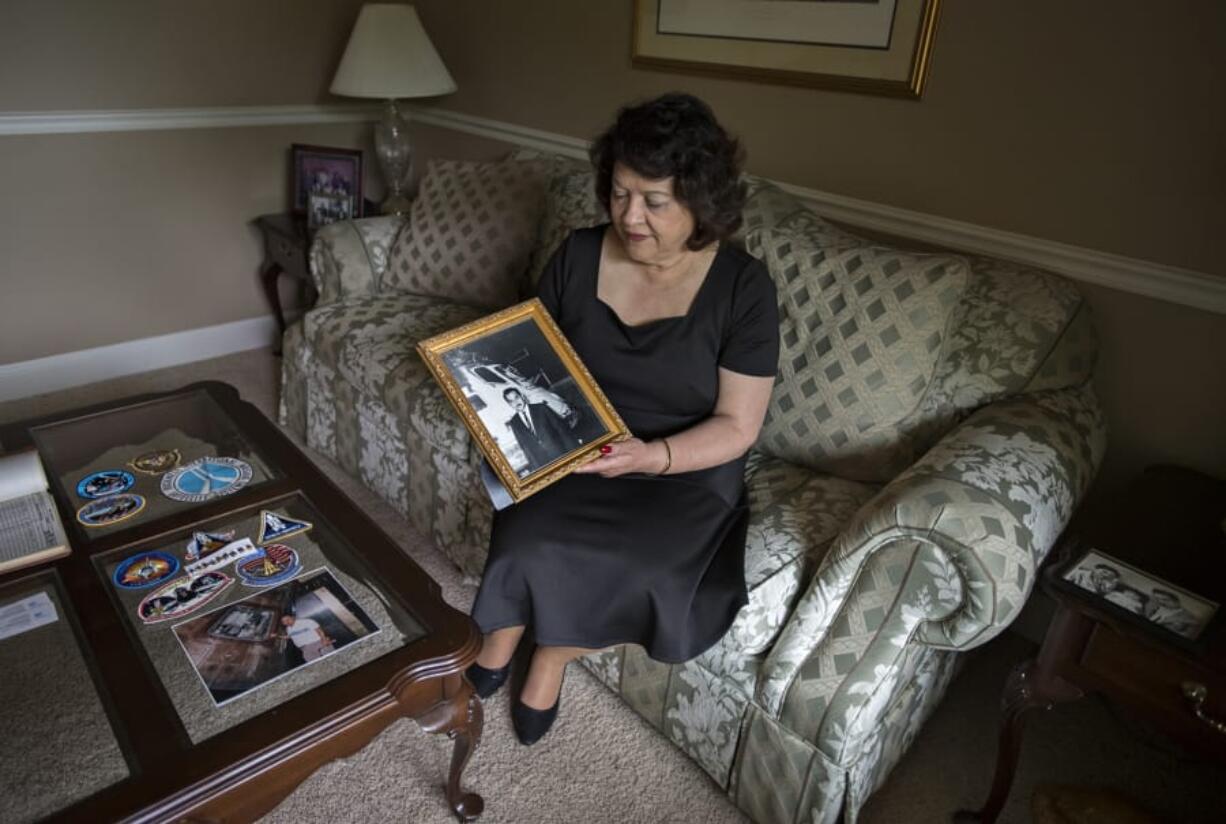 Libby Montoya-Bunkley of Salmon Creek looks over a photo of her late father, Herb Montoya, as he is pictured with the Apollo 11 capsule he helped create, on Monday at her home in Vancouver. Her father was an engineer with Rockwell International.