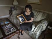 Libby Montoya-Bunkley of Salmon Creek looks over a photo of her late father, Herb Montoya, as he is pictured with the Apollo 11 capsule he helped create, on Monday at her home in Vancouver. Her father was an engineer with Rockwell International.