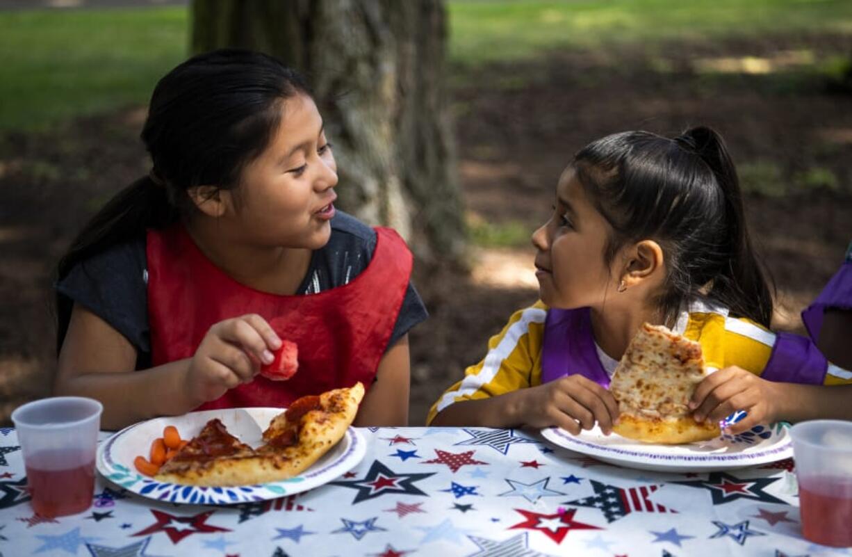 Dana Constanza, 10, left, and Alexa Bautista, 7, both of Vancouver, eat together during the Summer Playgrounds Program at Evergreen Park in Vancouver on Wednesday.