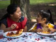 Dana Constanza, 10, left, and Alexa Bautista, 7, both of Vancouver, eat together during the Summer Playgrounds Program at Evergreen Park in Vancouver on Wednesday.