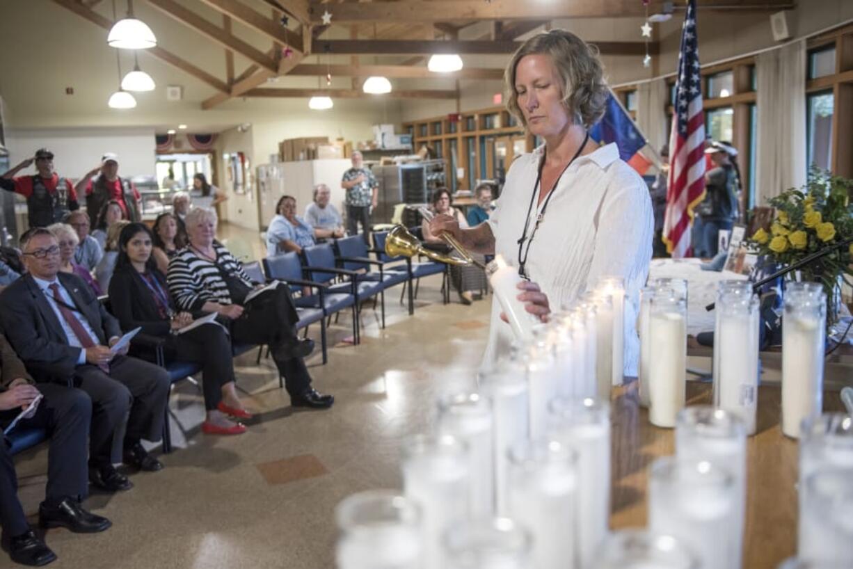 Kristen Saxton, a social worker at the Vancouver VA campus’ Community Living Center, lights candles to honor each of the 32 veterans who died at the facility in the past six months during Friday afternoon’s Remembering our Heroes event. At top, Darwin Goodspeed, director of the Portland VA Health Care System, holds an American flag that was presented to him at the end of Friday’s memorial service.